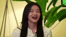 a young girl with long black hair is laughing with her mouth open .