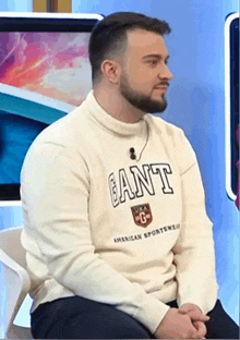 a man with a beard wears a sweater that says gant