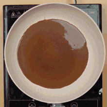a frying pan with a brown liquid in it sits on an induction stove top