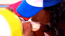a person wearing a blue hat is licking a baseball