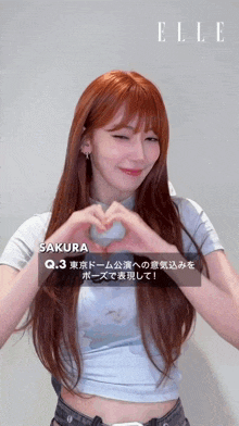 a woman with long red hair is making a heart shape with her hands .