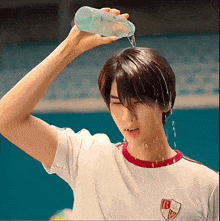a man is pouring water from a bottle on his head .
