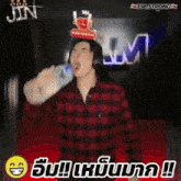 a man wearing headphones is drinking from a bottle with a crown on his head