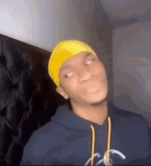 a young man wearing a yellow headband and a hoodie is making a funny face .
