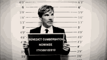 a man in a suit and tie holds up a sign that says benedict cumberbatch