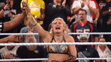 a woman in a wrestling ring holds up her fist in the air while a crowd applauds