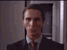 a man in a suit and tie is sitting in front of a window .