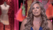 a woman in a blue tank top is making a funny face in front of a mannequin .