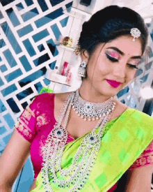 a woman wearing a green and pink saree and a necklace