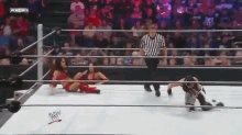 two women are wrestling in a wrestling ring while a referee looks on ..
