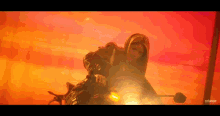 a woman in a leather jacket is riding a motorcycle in front of a red background .
