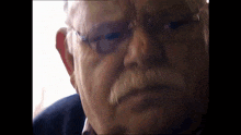 a close up of a man 's face with glasses and a white mustache