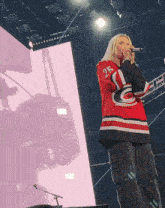 a woman singing into a microphone with the number 25 on the back of her shirt