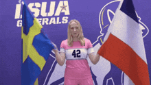 a woman in a pink jersey with the number 42 on it holds two flags