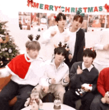 a group of people are posing for a picture in front of a merry christmas banner .