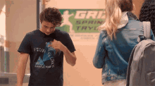 a boy wearing a pink floyd t-shirt is standing next to a girl in a denim jacket .