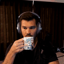 a man wearing headphones is drinking from a mug that has a girl on it