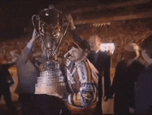 a man holds up a trophy that says coca cola on it
