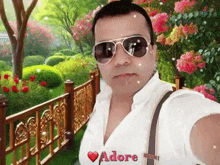a man wearing sunglasses takes a selfie in front of a fence with the word adore on the bottom right