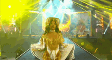 a woman in a gold and white dress is on a stage