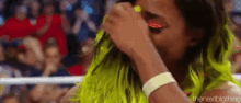 a woman in a neon green wig is covering her face with her hand .