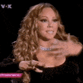 mariah carey is wearing a black dress and a necklace while talking on a television program .