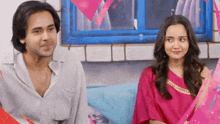 a man and a woman are sitting next to each other on a couch in front of a window .