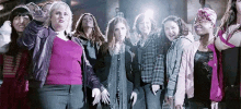 a group of women are standing next to each other in a room and giving the peace sign .