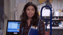 a woman wearing a name tag that says `` bobbie '' is standing in front of a computer in a store .