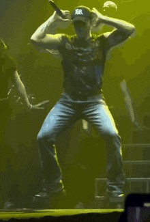 a man wearing a black hat with the letter r on it is squatting on a stage