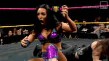 a woman in a wrestling ring is holding a can of soda in her hand