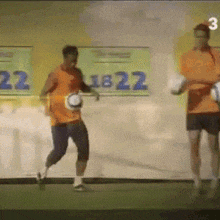 a man in an orange shirt is running with a soccer ball