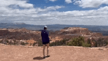 a person is standing on top of a mountain looking at the landscape .