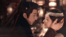 a man and a woman are looking into each other 's eyes in a dark room .