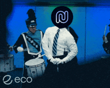 a man in a blue marching band uniform is playing drums with a n on his head