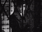 a black and white photo of a man in a suit and hat behind bars