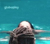 a woman is swimming in a pool with a globeplay logo on the bottom .
