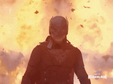 a man in a superhero costume is standing in front of a fire and a sign that says keluang man