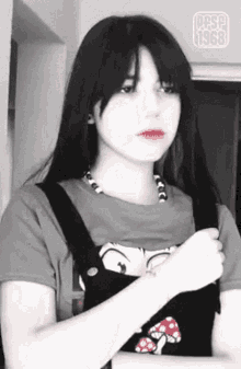 a girl with long black hair is wearing overalls and a t-shirt with a mushroom on it .