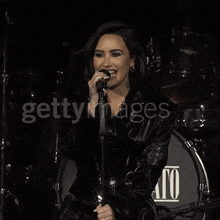 a woman singing into a microphone in front of a drum that says ato