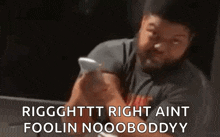 a man with a beard is sitting at a table looking at his phone .