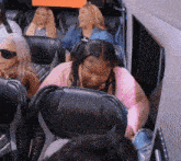 a group of people are sitting on a bus and one of them is wearing a pink sweater