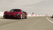 a red sports car is driving down a road with a white line on it