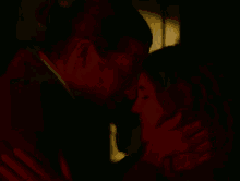 a man and a woman are looking at each other in a dark room