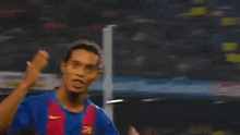 a soccer player is blowing a kiss to the camera while wearing a blue and red jersey .