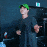 a man wearing a green tekken hat stands in front of a fire extinguisher