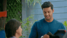 a man in a blue sweater is talking to a woman in front of a blue building