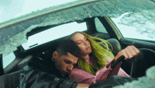 a man and a woman are sitting in a car with a broken windshield