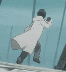 a person in a white coat is standing next to a pole and holding a gun .