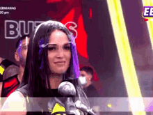 a woman wearing a face shield stands in front of a microphone .